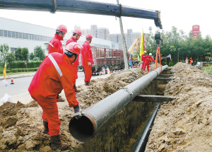 在徐州至沛县,丰县天然气管道工程施工现场,工人们正忙着吊装管道.